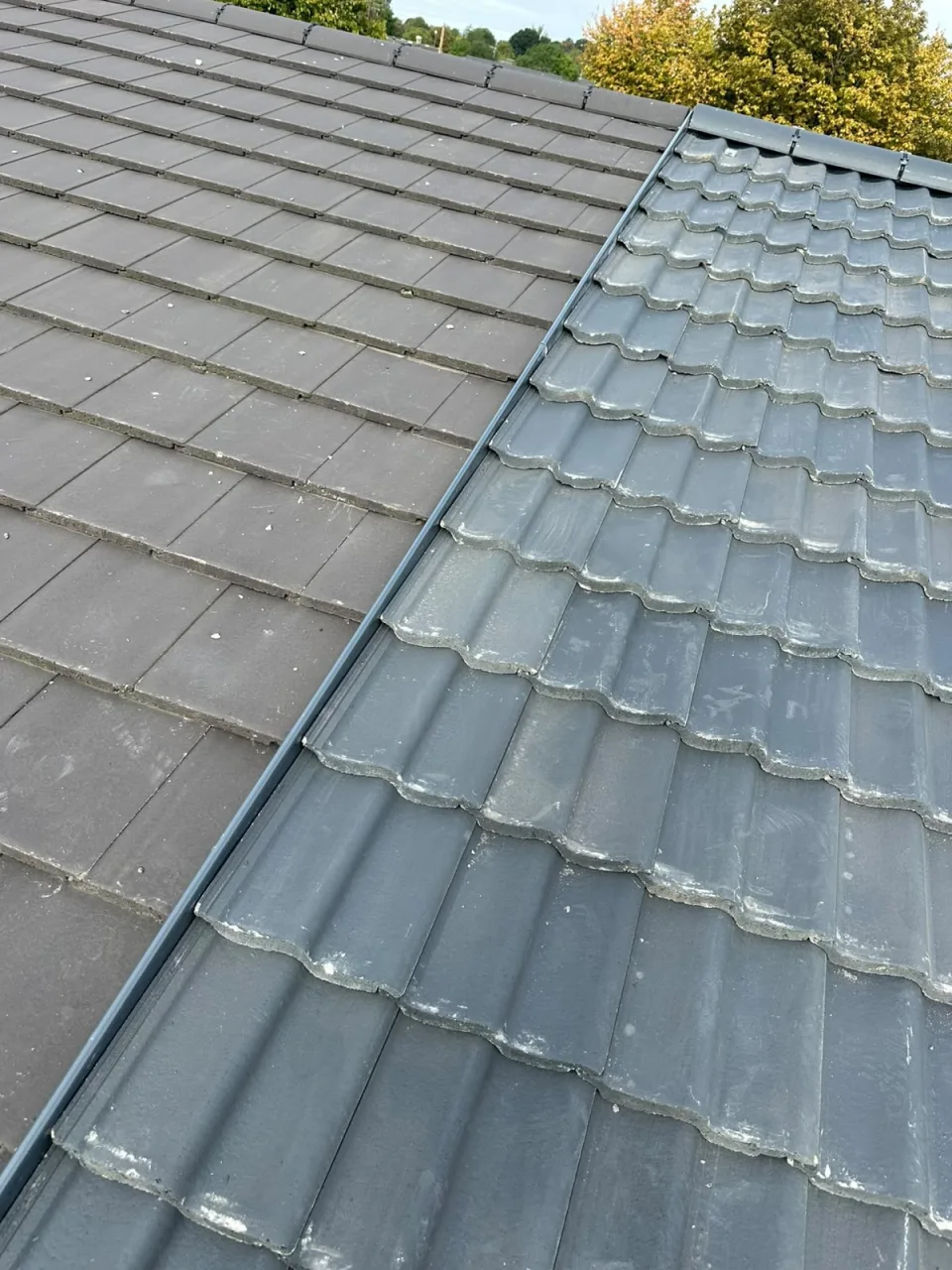 A roof valley between flat concrete tiles and grey pantiles
