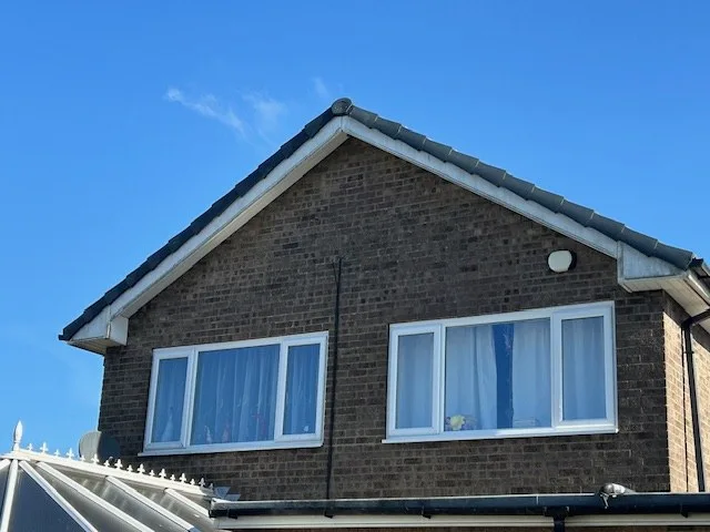 A tiled gable with white fascia and bargeboard against a clear sky