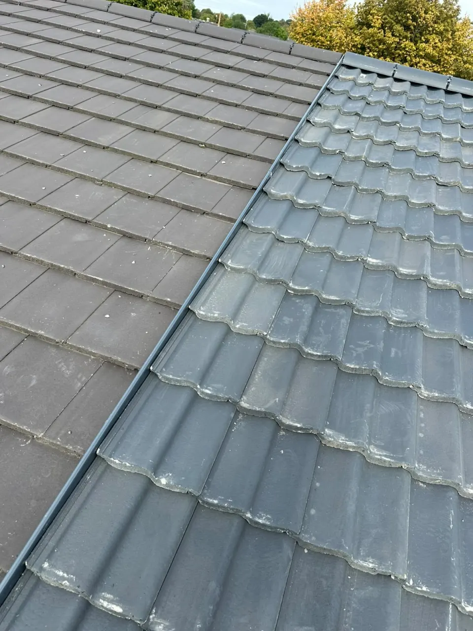 A roof valley between flat concrete tiles and grey pantiles