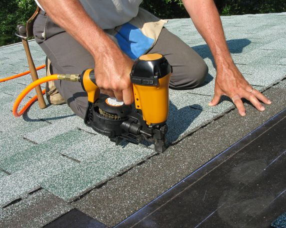 Roofer using a nail gun to repair a roof